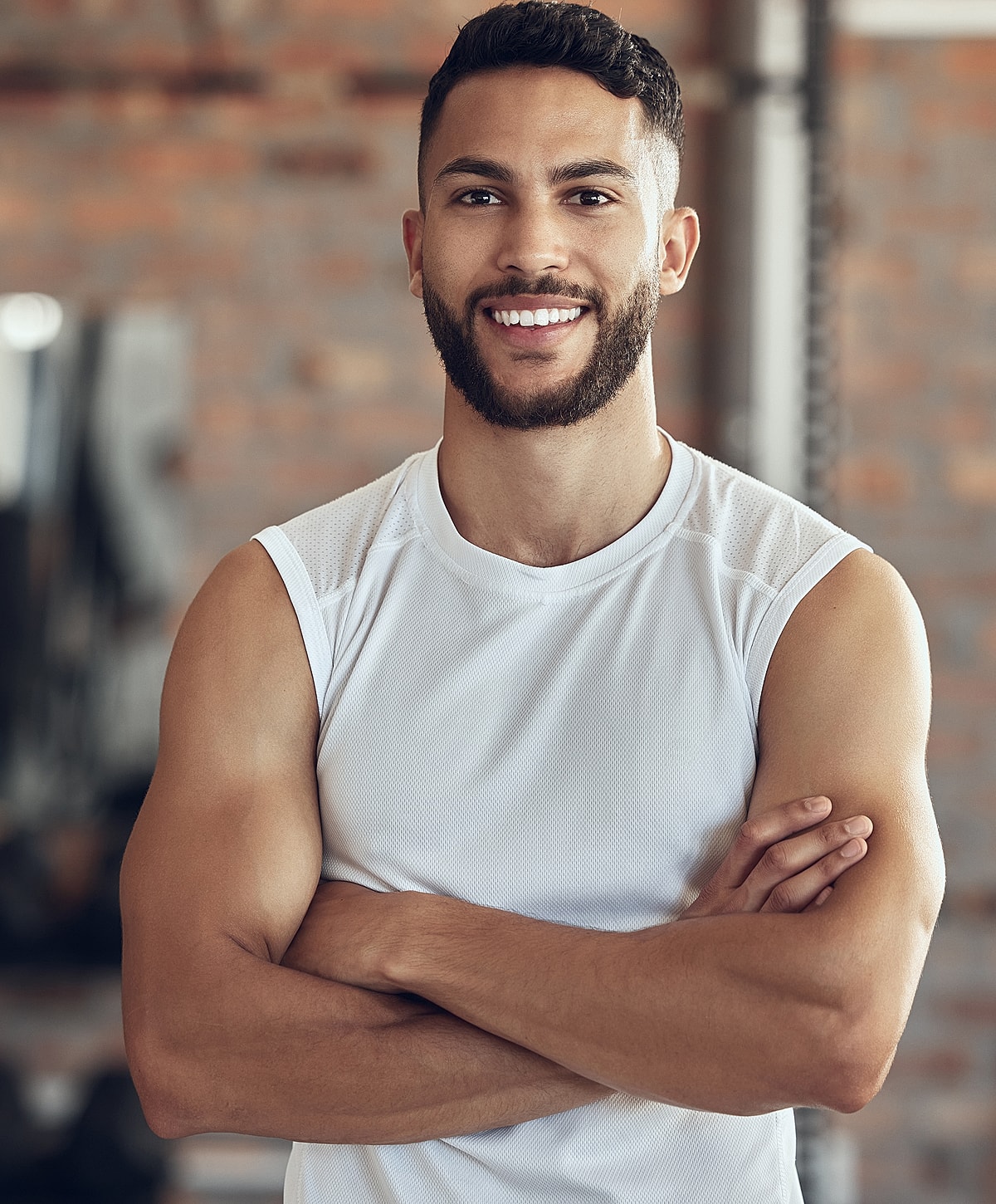 Smiling man in gym attire with crossed arms.