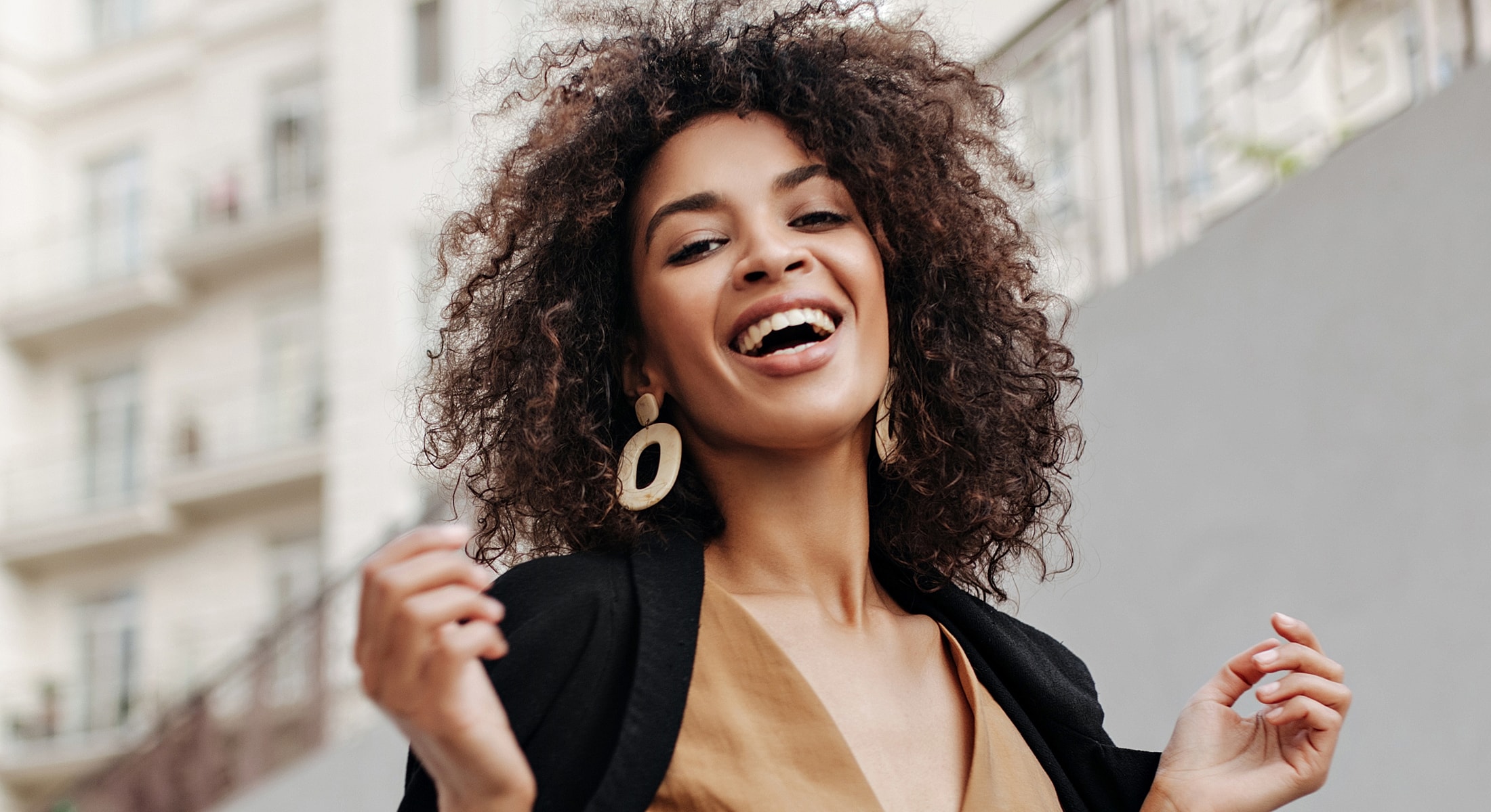 Smiling woman with curly hair outdoors.